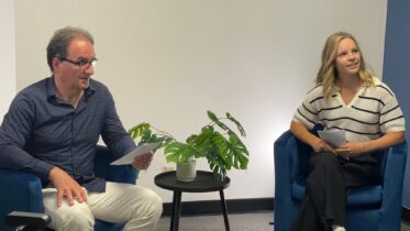 man and woman in office sitting in chairs about to do a presentation